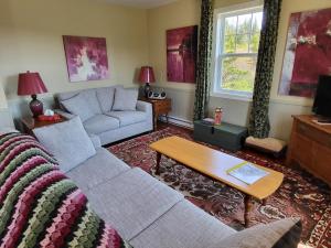 a living room with a couch and a table at Skerwink Trail House in Port Rexton