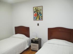 Un dormitorio con dos camas y un cuadro en la pared. en Miraflores Pacific Hotel, en Lima