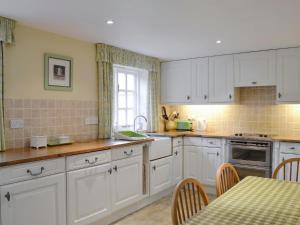 a kitchen with white cabinets and a table with chairs at The Cottage - Sinnington in Sinnington
