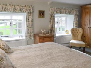 a bedroom with a bed and a chair and windows at The Cottage - Sinnington in Sinnington