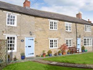 an old stone house with white windows and a yard at The Cottage - Sinnington in Sinnington