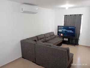 a living room with a couch and a flat screen tv at Casa arcilla clima total Starlink zona Aeropuerto in Villa Juárez