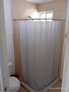 a white shower curtain in a bathroom with a toilet at Casa arcilla clima total Starlink zona Aeropuerto in Villa Juárez