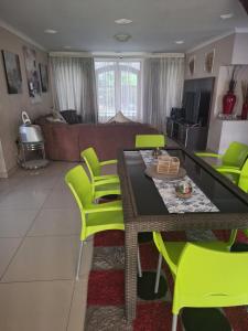 a living room with a table and yellow chairs at Caribbean Estate Guest House B11 in Port Edward