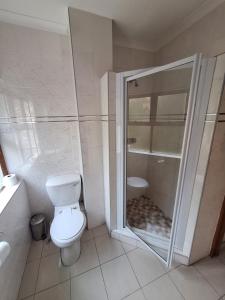 a white bathroom with a toilet and a shower at Caribbean Estate Guest House B11 in Port Edward +5 photos