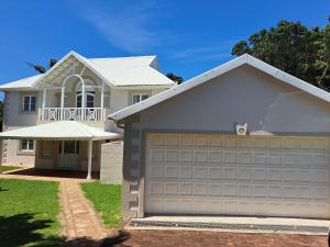 a white house with a garage at Caribbean Estate Guest House B11 in Port Edward