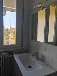 a bathroom sink with a mirror and a window at Attico nel Cuore di Modena in Modena