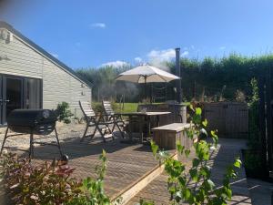 a patio with an umbrella and a table and chairs at Stable End in Liskeard