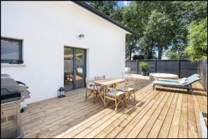un patio con mesa y sillas en una terraza de madera en Villa Mimosa et SPA, en Andernos-les-Bains
