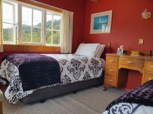 a bedroom with a bed and a dresser and a window at Westway Homestay in Runanga