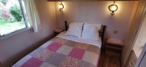 a small bedroom with a bed with a quilt on it at La Petite Maison dans La Mégie Tiny House in Troche