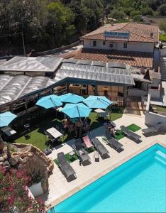 an aerial view of a swimming pool with blue umbrellas and chairs at Auberge de Cannedda in Sari Solenzara