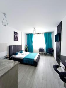 a bedroom with a bed and blue curtains and a desk at Eduard Elegance Rin Studios in Bucharest