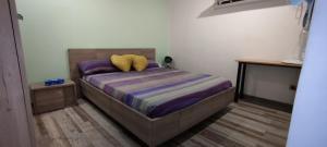 ein Schlafzimmer mit einem Bett mit violetter Bettwäsche und gelben Kissen in der Unterkunft Mayecha in Dzaoudzi