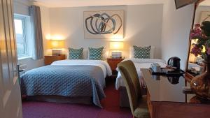 a hotel room with two beds and two lamps at Stansted Lodge Elsenham in Elsenham