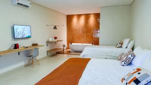 a bedroom with two beds and a bath tub at Suites Anacã in Bonito