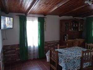 a room with a table and a window with green curtains at Casaluma in Jose De San Martin