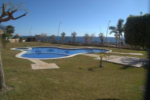 a swimming pool in a park with palm trees at Ático con vistas al Mediterráneo in Isla Plana