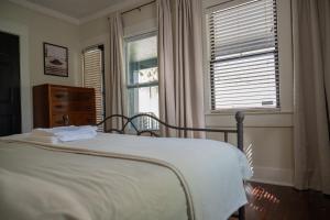 a bedroom with a bed and a dresser and two windows at Historic Orlando Casita Love Apt A with backyard in Orlando