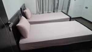 two beds with white sheets and pillows in a room at Appt Fes centre ville in Fez