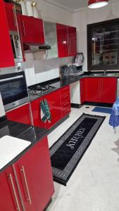 a kitchen with red cabinets and a rug on the floor at Appt Fes centre ville in Fez