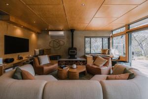a living room with two couches and a tv at Wildacres Luxe 40 Acre Australian bush escape with private cliffs in Blackheath