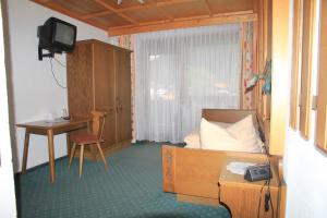 a room with a bed and a desk and a television at Berghaus Maria in Pettneu am Arlberg