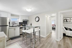 a kitchen with white cabinets and a counter with stools at Separate 3BR Family Friendly Apartments, Separate Floors, 5 Minutes Walk to The Fallsview with Free Parking & Wine in Niagara Falls +16 photos