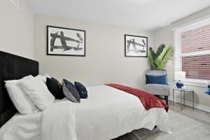 a white bedroom with a bed and a chair at Separate 3BR Family Friendly Apartments, Separate Floors, 5 Minutes Walk to The Fallsview with Free Parking & Wine in Niagara Falls