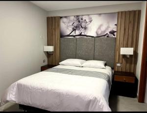 a bedroom with a white bed and a painting on the wall at Hotel Residencial Dentus in Tacna