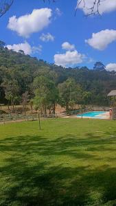 a grassy field with a swimming pool and trees at Suite 5 in Nova Friburgo