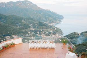 a group of tables and chairs on a balcony with the ocean at Hotel Bonadies in Ravello