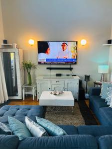 a living room with a blue couch and a flat screen tv at Creole Cottage Uptown in New Orleans