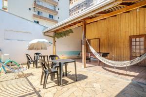 eine Terrasse mit Tischen und Stühlen und einer Hängematte in der Unterkunft Piscina e mar em único lugar in Penha
