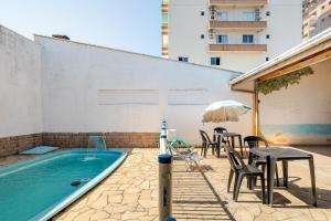 einen Pool mit einem Tisch, Stühlen und einem Sonnenschirm in der Unterkunft Piscina e mar em único lugar in Penha
