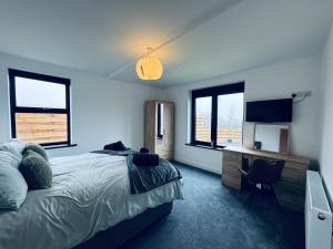 a bedroom with a bed and a desk and windows at Silverbirch Cottage - 3 Bedrooms - Sleeps 6 in Frizington