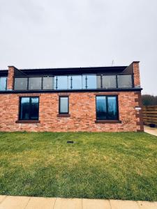 a brick house with a balcony on top of a yard at Silverbirch Cottage - 3 Bedrooms - Sleeps 6 in Frizington