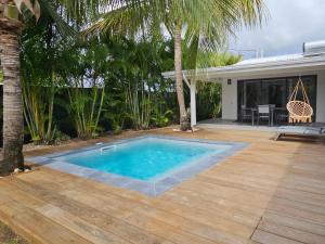 a swimming pool with a wooden deck and a house at Kaza Lenah villa 2 chambres dont une en mezzanine, piscine et cuve tampon, Saint-François in Saint-François