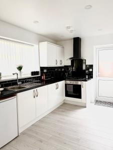 a kitchen with white cabinets and black appliances at Cozy getaway in heart of warwick in Warwick