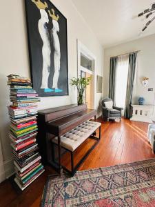 a living room with a piano and a stack of books at Creole Cottage Uptown in New Orleans
