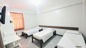 a hospital room with three beds and a window at Pousada Central in Feira de Santana