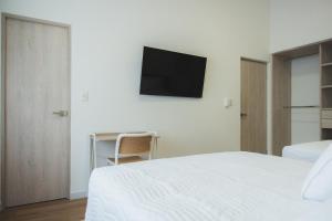 a bedroom with a bed and a tv on the wall at Casa Serena in Ibagué