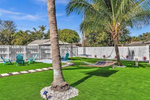 a hammock in a yard with two palm trees at Dream Hollywood Beach Retreat With Jacuzzi and Fire Pit in Dania Beach
