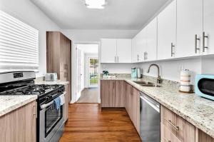 a kitchen with white cabinets and a stove top oven at Dream Hollywood Beach Retreat With Jacuzzi and Fire Pit in Dania Beach