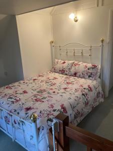 a bedroom with a bed with a floral bedspread at Rose Cottage in Hamilton