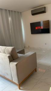 a couch in a room with a television on the wall at Casa da Marília in Porto Seguro