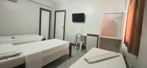 a white room with two beds and a mirror at Pousada Central in Feira de Santana