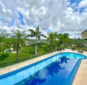 a swimming pool with palm trees in the background at Apartamento de um quarto com varanda externa in Bananeiras +12 photos