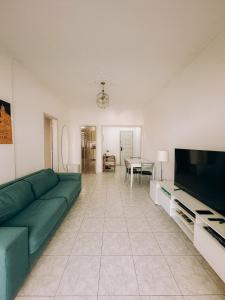 a living room with a green couch and a flat screen tv at Apto Amplo e confortável no centro de Salvador in Salvador