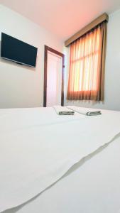 a white bed in a room with a window at Pousada Central in Feira de Santana